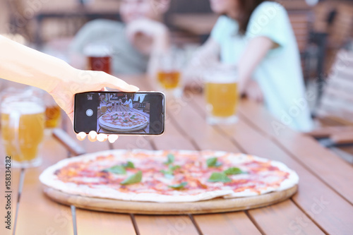 Girl making photo of pizza ...