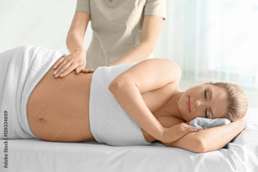 Young beautiful pregnant woman having massage in spa salon Young beautiful pregnant woman having massage in spa salon