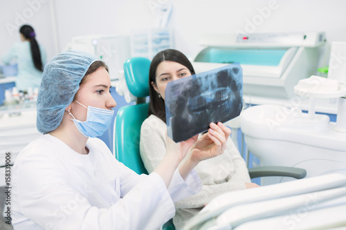 Doctor talking with patient and showing a radiograph in stomatology clinic