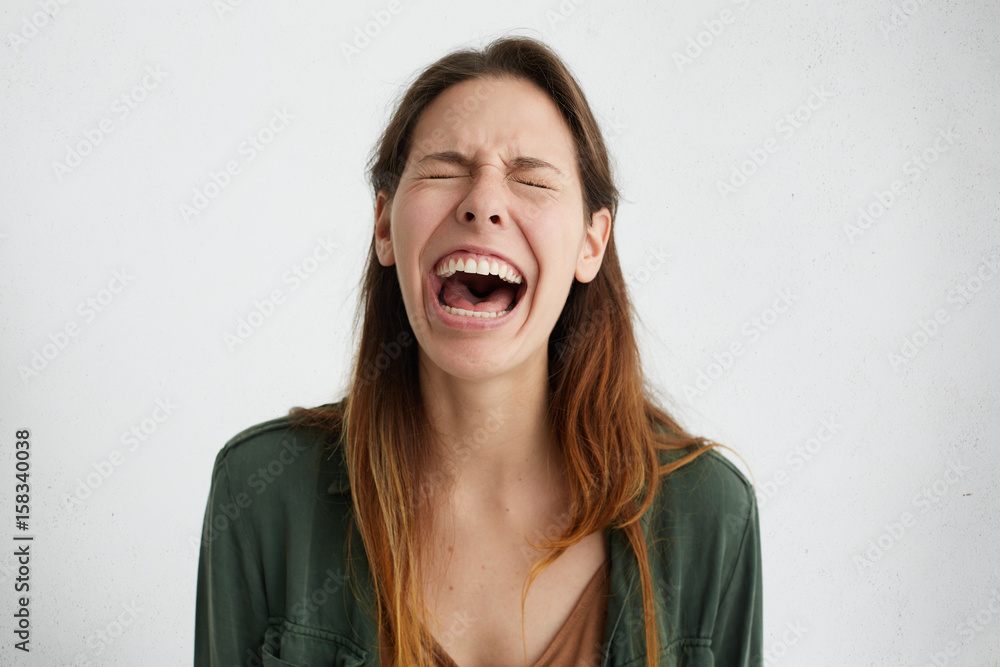 Stressful woman closing her eyes while crying having opened mouth feeling tension looking upset having grief. Crying woman regreting what she done. Sorrowed female isolated over white background Stressful woman closing her eyes while crying having opened mouth feeling tension looking upset having grief. Crying woman regreting what she done. Sorrowed female isolated over white background