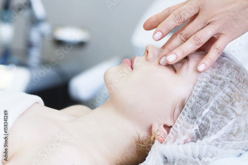 Close-up portrait of a young woman getting spa treatment and face massage