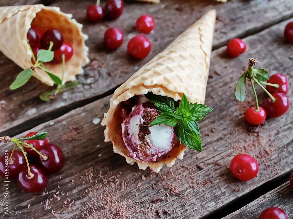 Homemade ice cream cherries and chocolate in a waffle cone, fresh cherries on old wooden table - left view