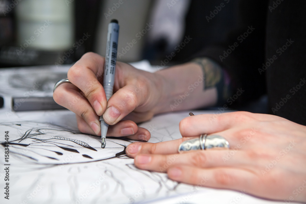 Obraz premium Girl tattoo artist draws a sketch. Close-up of hands