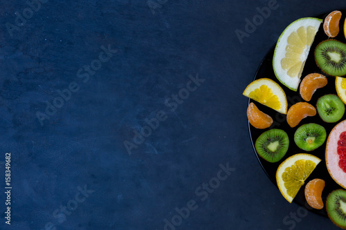 delicious cut bright sweet acidic citrus fruits in the plate with the edge of a dark blue background with place for text labels copyspace