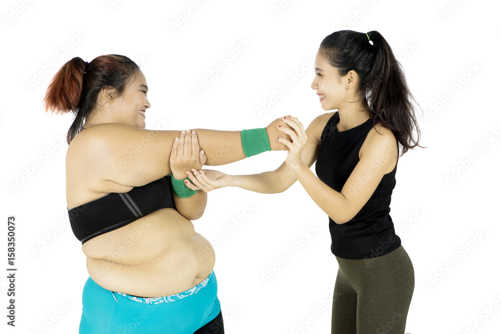 Instructor helping fat woman exercising Instructor helping fat woman exercising