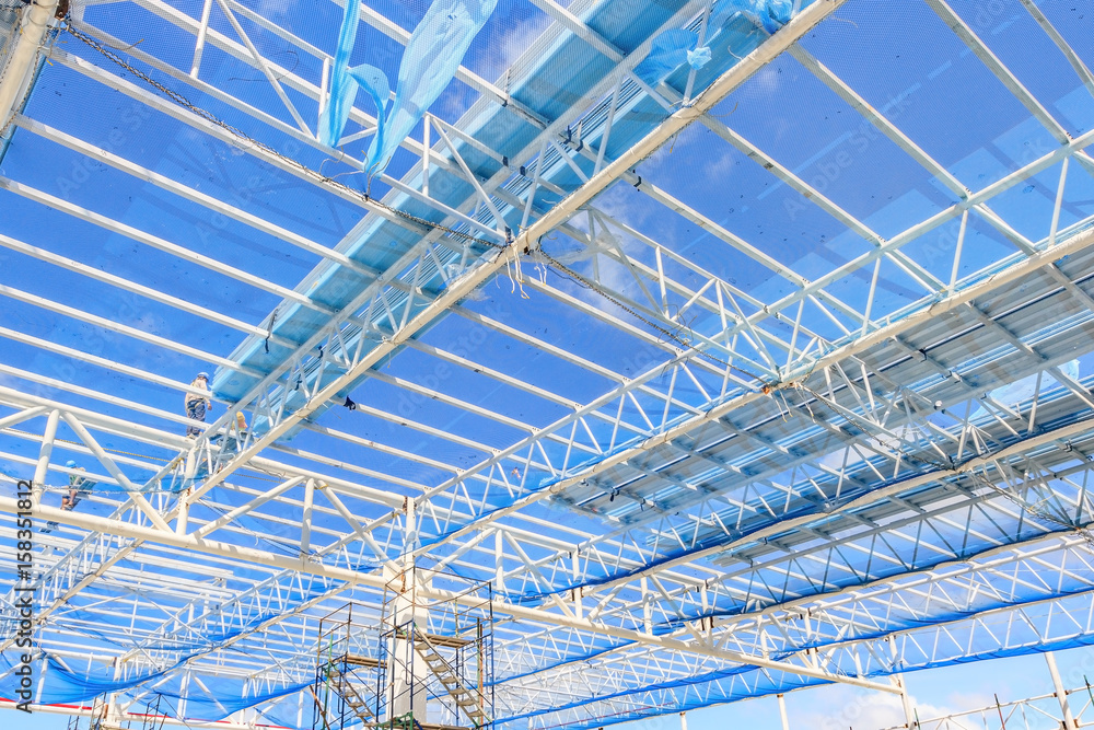 Structure of steel roof frame for building construction on blue sky background.