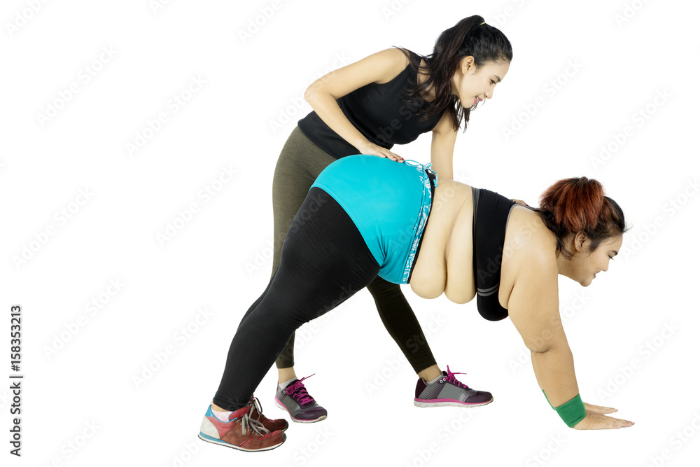 Trainer helping obese woman bending Trainer helping obese woman bending