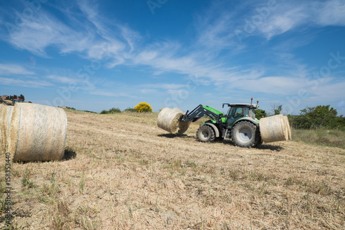 Obraz na płótnie Traktor auf einem Feld mit Heuballen w salonie