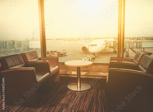 Fotografiet Departure lounge at the airport with seating and table with aircraft preparing f