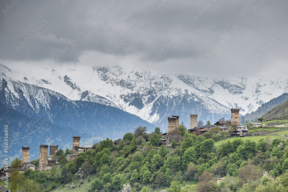 View of the Svanetian towers  in Mestia village against snowy mountains. Upper Svaneti, Georgia.