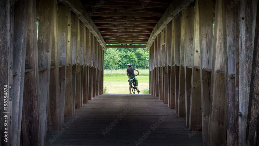 Radfahrerin durch eine alte Holzbrücke