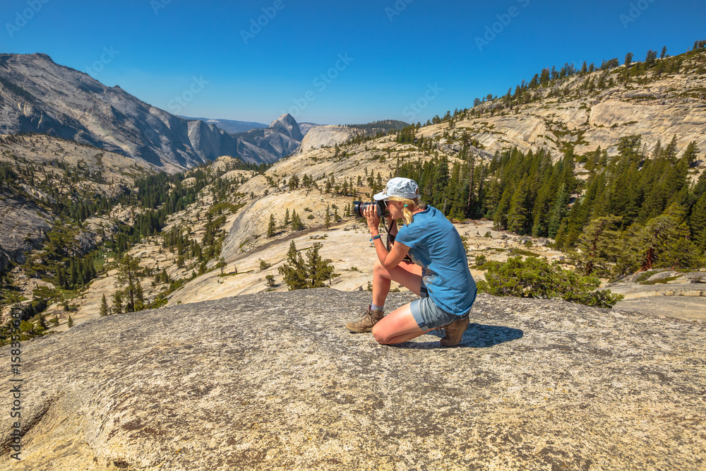 Travel photographer takes shot of north side Half Dome on Olmsted Point. Tioga Road in Yosemite National Park, California, USA. Nature photographer taking pictures outdoors during hiking trip.