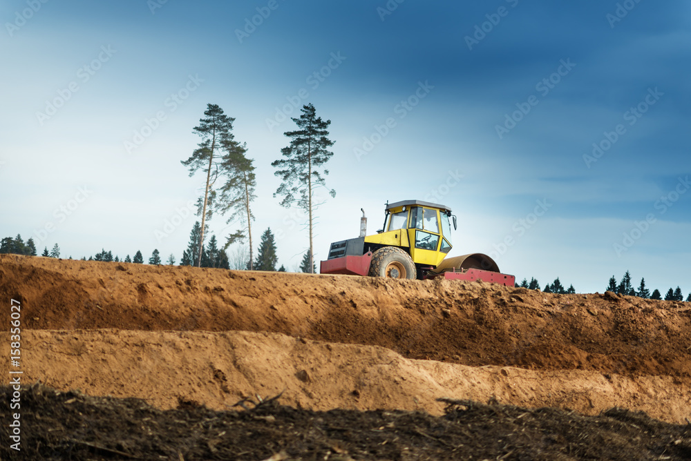 Fototapeta premium Large view on the compactor working on the new road construction site