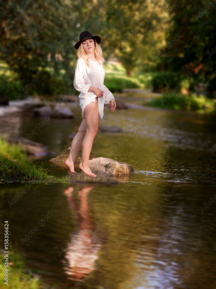 Young woman in the white dress in the middle of a creek.. Young woman in the white dress in the middle of a creek..