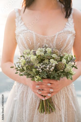 Fototapeta Naklejka Na Ścianę i Meble -  Wedding bouquet in the hands of the bride with lots of greenery