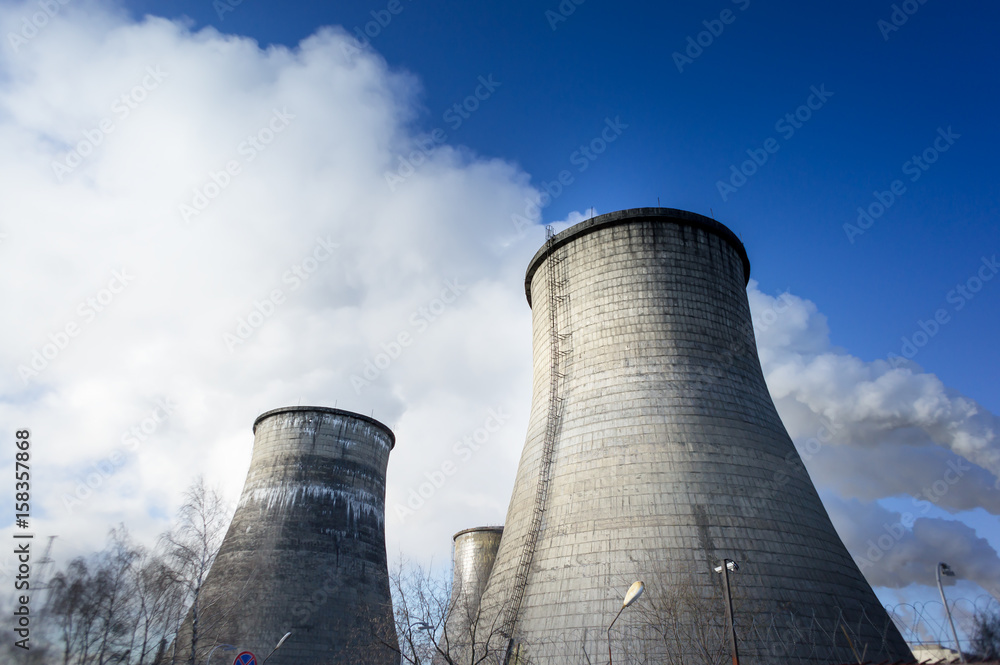 Two cooling towers emitting steam, with a blue sky background Two cooling towers emitting steam, with a blue sky background