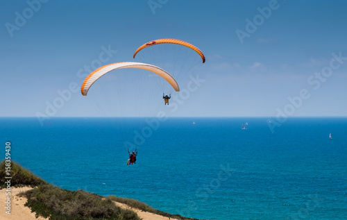 Tandem paragliding above Mediterranean sea on blue sky background