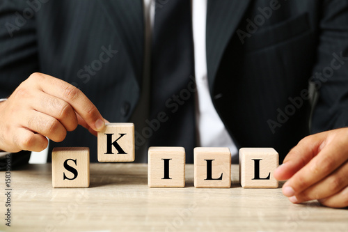 Businessman holding wooden cube with word Skill
