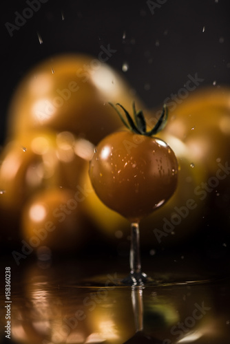  Yellow tomatoes on black background ,water drops , mirror