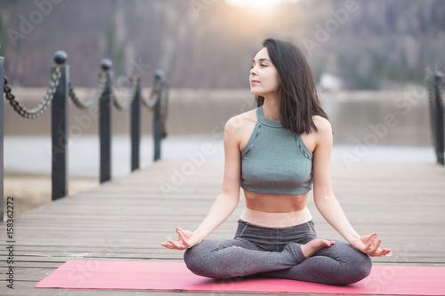 Young girl doing yoga or fitness exercise outdoor in nature