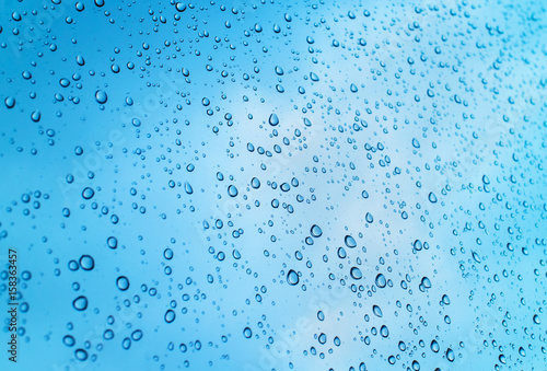 Drops of heavy rain on glass with clearly sky background