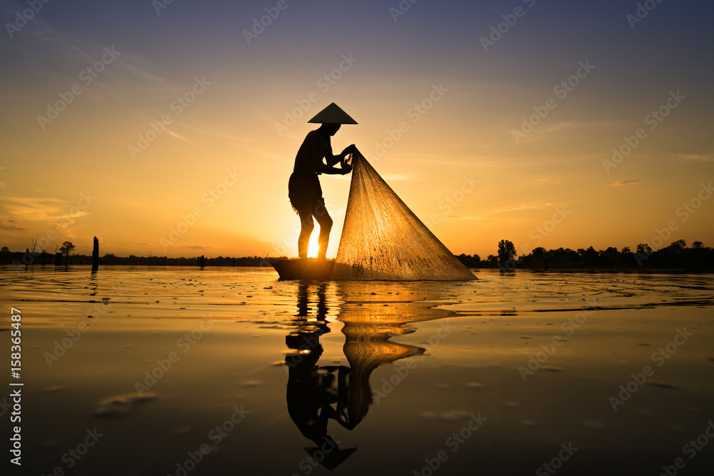 Silhouette of Fisherman catching fish in lake by using fishing net