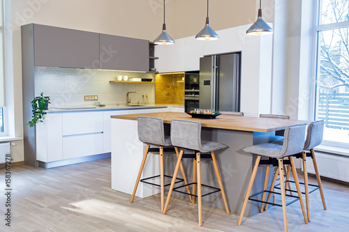 Modern kitchen design in light home interior. Kitchen island in the room. Kitchen and living room. European furniture, design, technologies. Float Pendant Light. Bar stools. Appliances and decorations