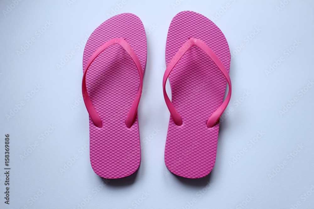Des paires de chaussures de plage tong en couleurs sur fond blanc