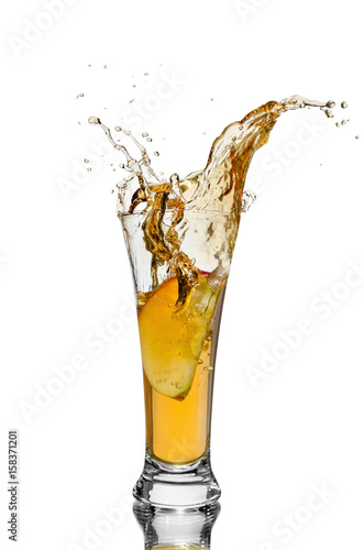 a piece of Apple falling into a glass of juice on white isolated background