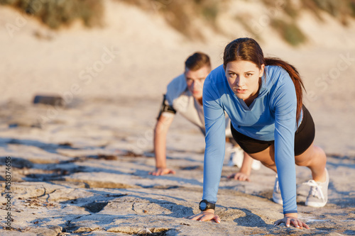 Plakat Young couple doing push ups on ocean beach