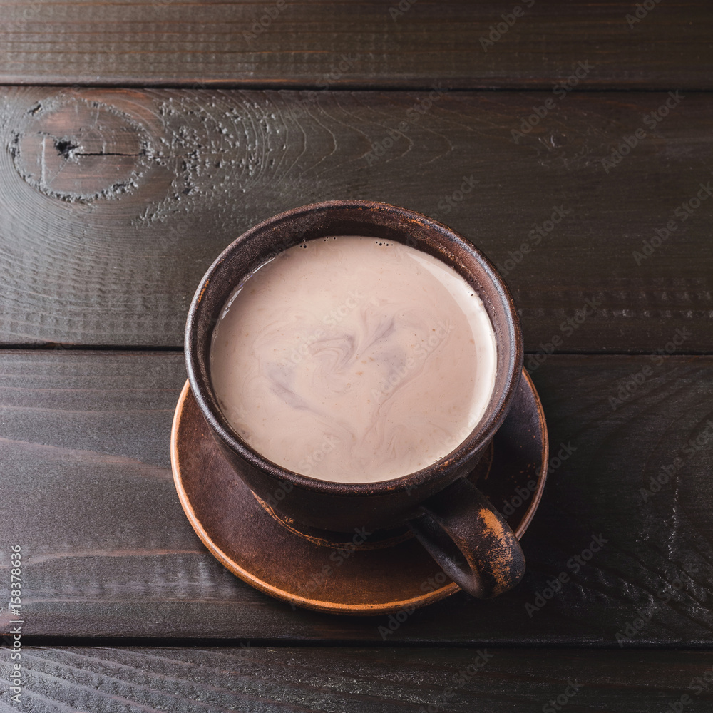 Hot chocolate or cocoa drink in clay cup, on dark brown wooden table Hot chocolate or cocoa drink in clay cup, on dark brown wooden table