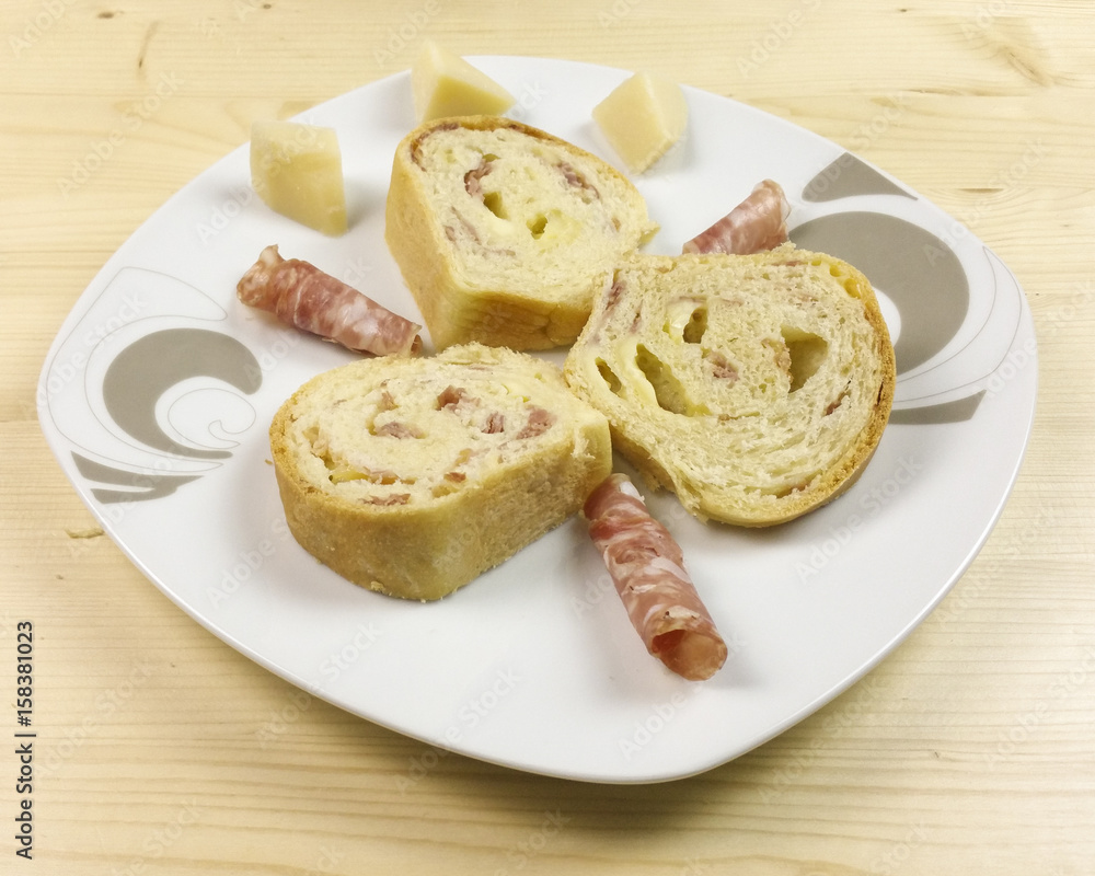 savory cake with salami, ham and cheese on wooden background - top view