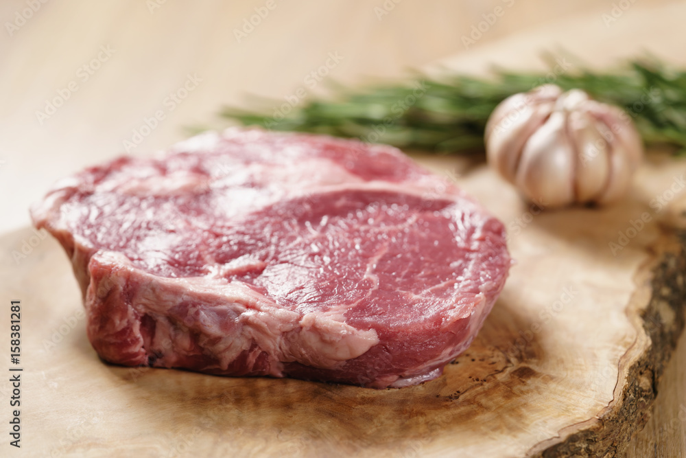 raw rib eye steak on board closeup, shallow focus