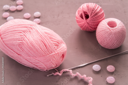 Pink knitting with crochet hook on the grey background photo