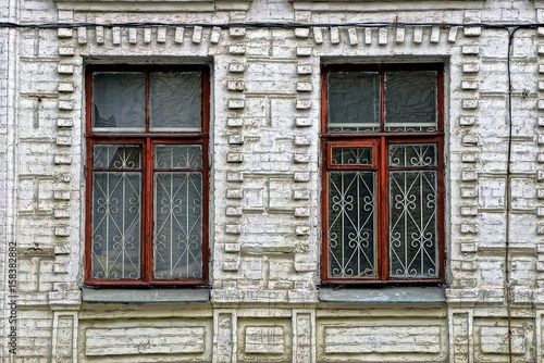 Старые разбитые окна  с решёткой на кирпичной стене здания © butus