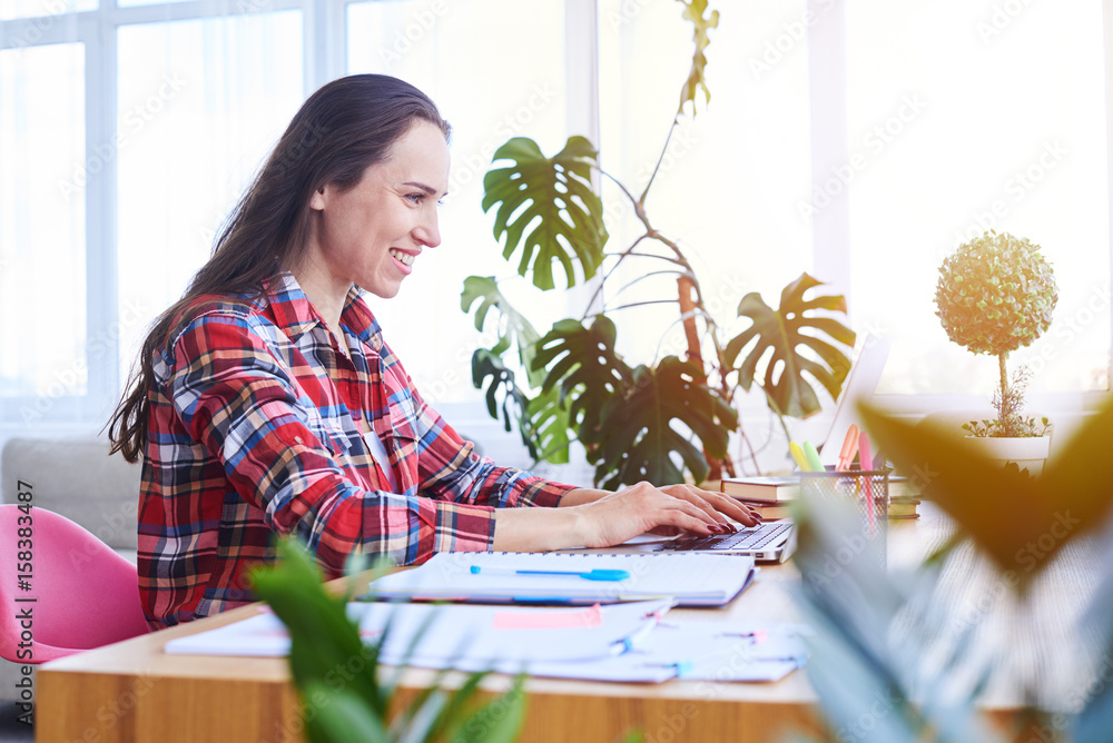 Concentrated madam working in laptop while sitting in desk Concentrated madam working in laptop while sitting in desk