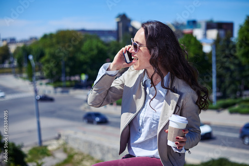 Pleasant brunet talking on phone while holding cup of coffee © ArtFamily