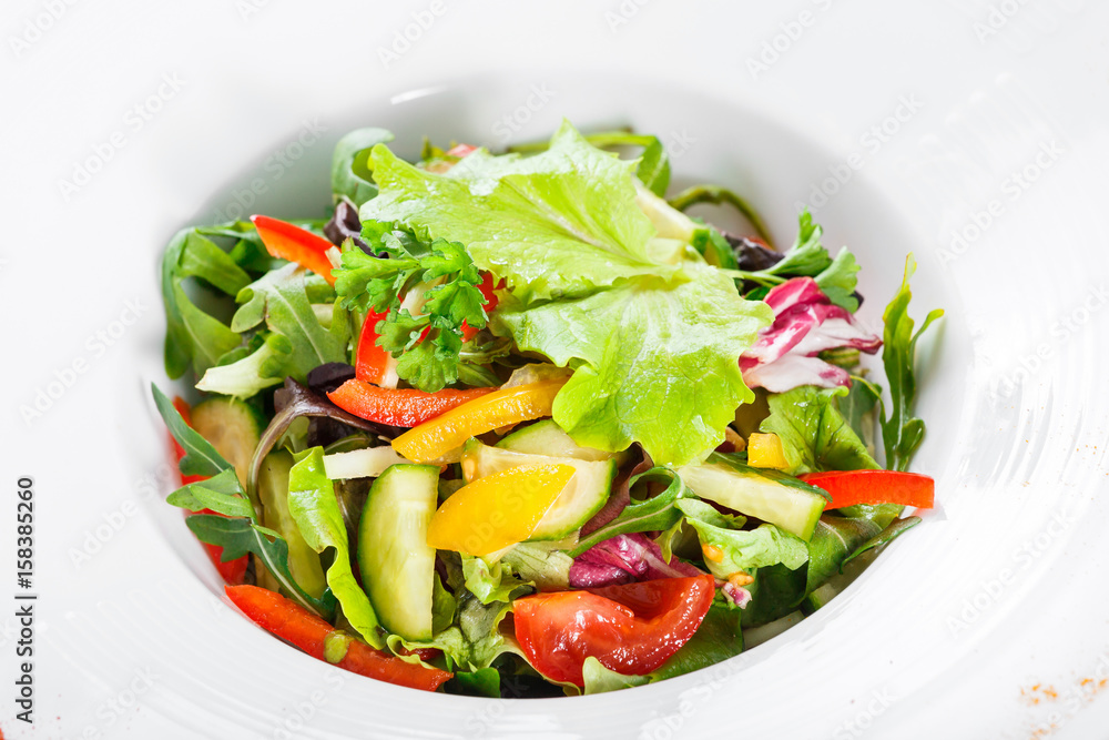 Fresh salad with cauliflower, arugula, lettuce, cherry tomatoes, cucumber, sweet pepper on wooden background. Top view