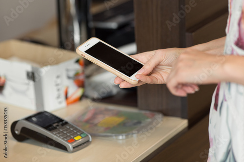 Close up of woman paying with NFC technology on mobile phone
