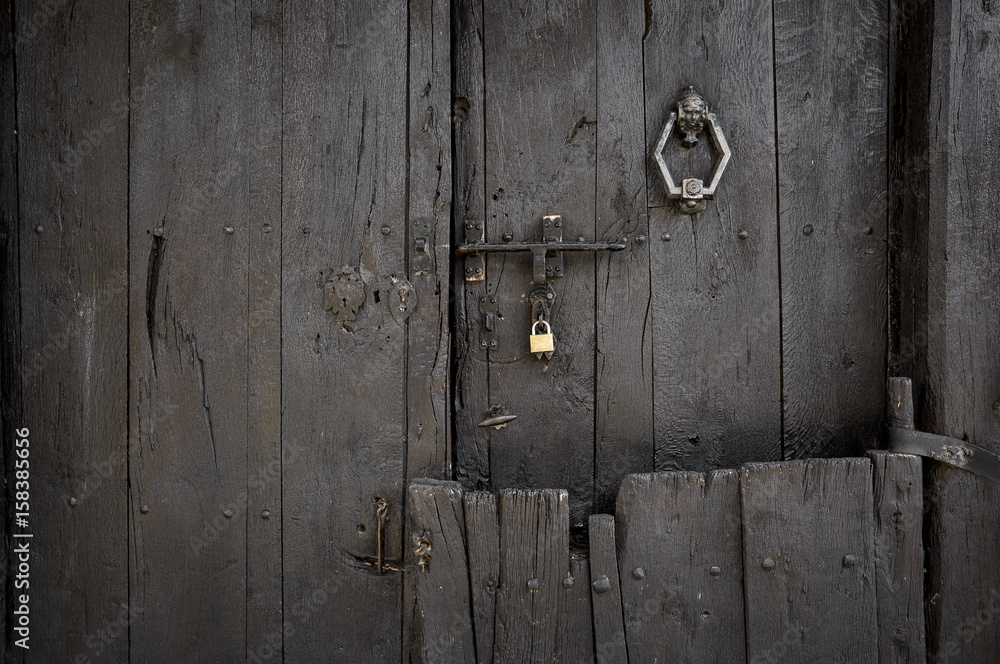 ancient dark brown wooden door with a door knocker a padlock and a bolt ancient dark brown wooden door with a door knocker a padlock and a bolt