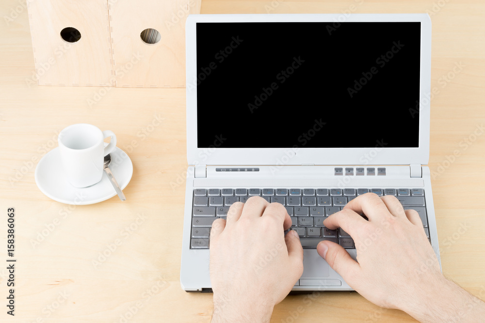 Business man working on laptop on brown wooden workplace table with cup and folders Business man working on laptop on brown wooden workplace table with cup and folders
