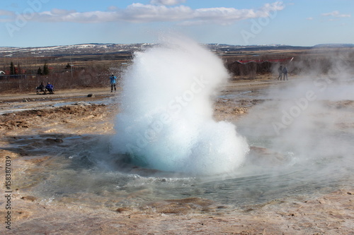 A jet of water and air is violently forced out through the hole in the rocks.