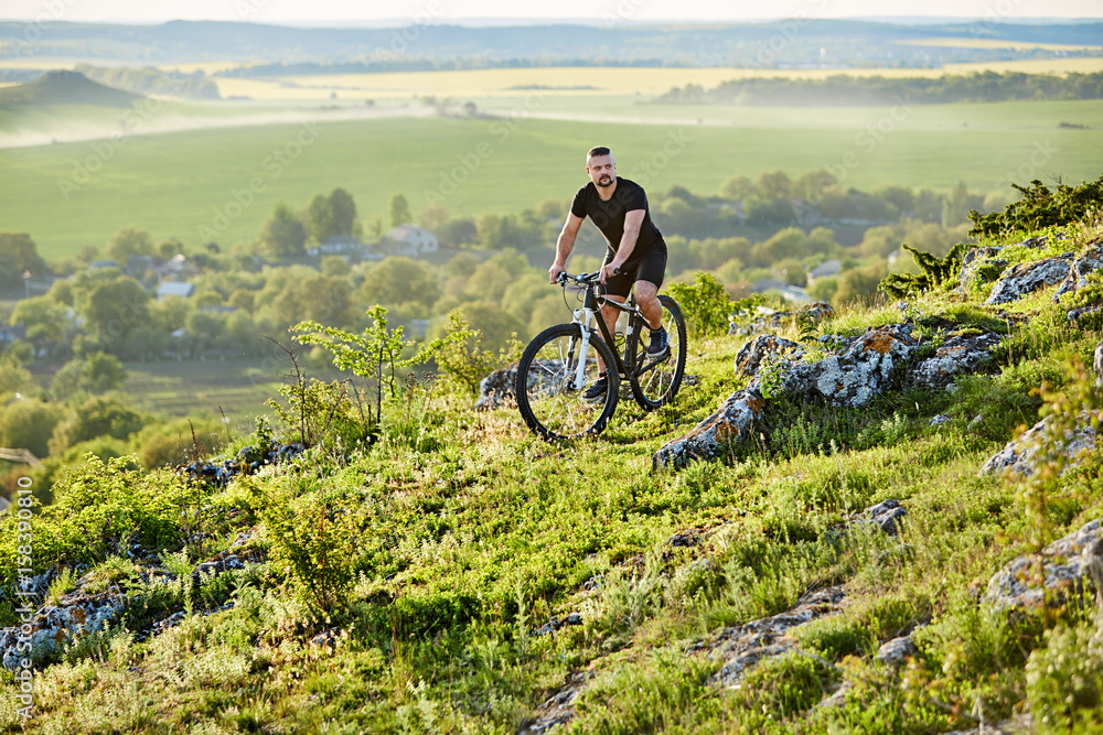 Obraz premium Extreme mountain cyclist riding bike on rocky trail in the countryside.