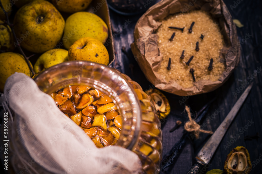 Ingredients tinctures Fruits twigs quince sugar cloves vanilla wooden table Ingredients tinctures Fruits twigs quince sugar cloves vanilla wooden table