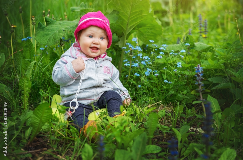 Baby girl sitting in tall green grass under the mug. Baby girl sitting in tall green grass under the mug.