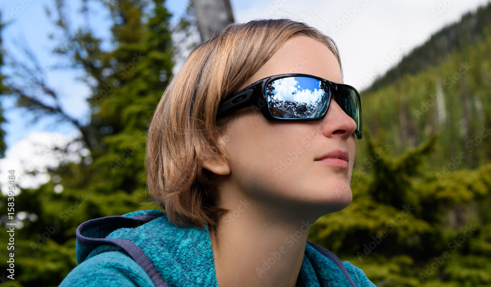 Portrait go beautiful young hiking woman looking at snowy mountains at summer season. Reflection in sunglasses Portrait go beautiful young hiking woman looking at snowy mountains at summer season. Reflection in sunglasses