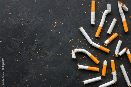 Broken cigarettes and tobacco on a black background with space for text