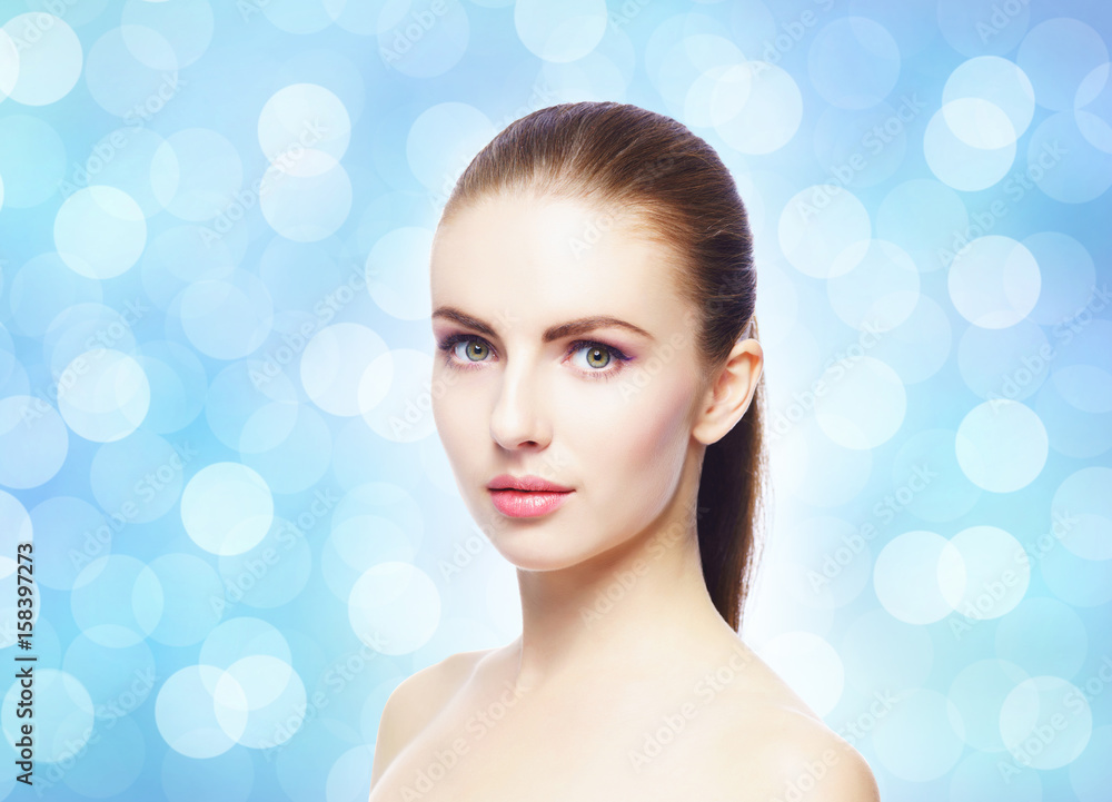 Naklejka premium Portrait of young, beautiful and healthy woman: over blue blurry background. Healthcare, spa, makeup and face lifting concept.