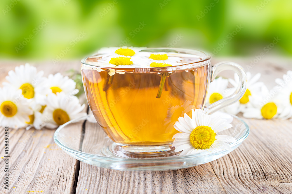 cup of camomile tea and camomile flowers on wooden background cup of camomile tea and camomile flowers on wooden background