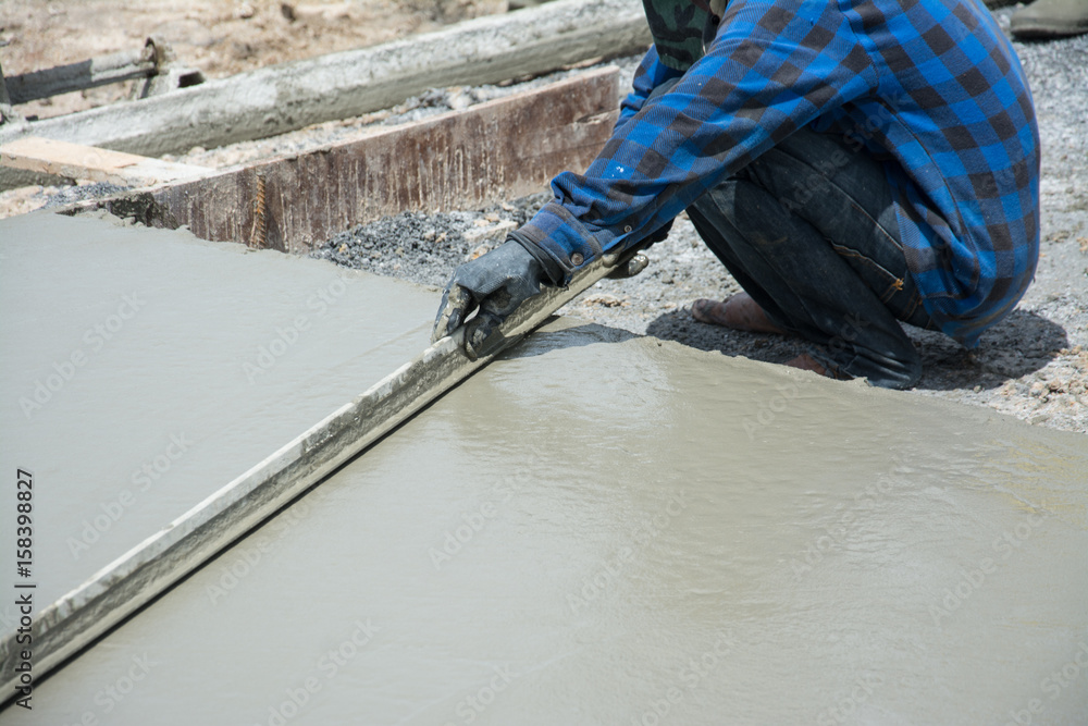 Leveling concrete with trowels, laborer spreading poured concrete Leveling concrete with trowels, laborer spreading poured concrete